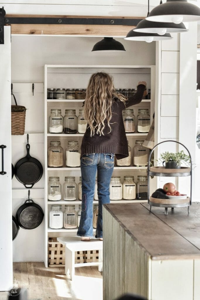 Well-organized pantry with labeled glass jars and open wooden shelving.
