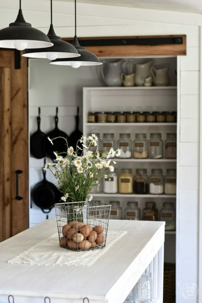 Narrow pantry featuring open wooden shelves and glass jar storage for dry goods.