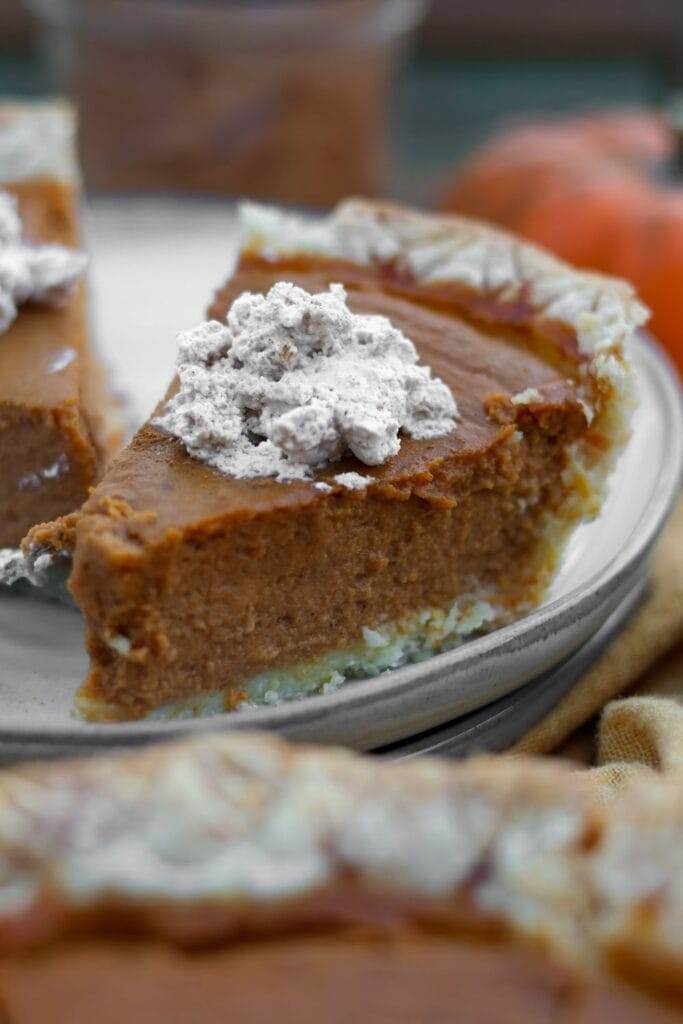 a slice of pumpkin pie on a plate topped with whipped cream