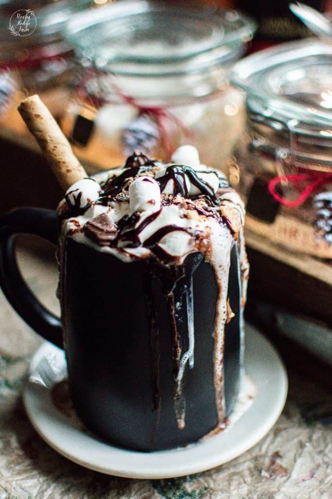 Black Mug Filled with Hot Chocolate and topped with whip cream and chocolate sauce