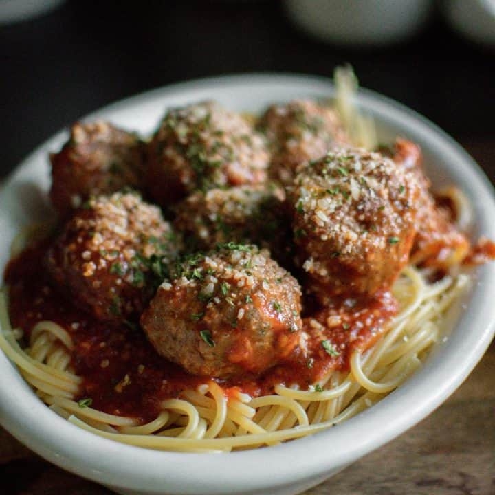 A white bowl filled with spaghetti noodles and topped with Italian Meatballs made from Homemade Recipe