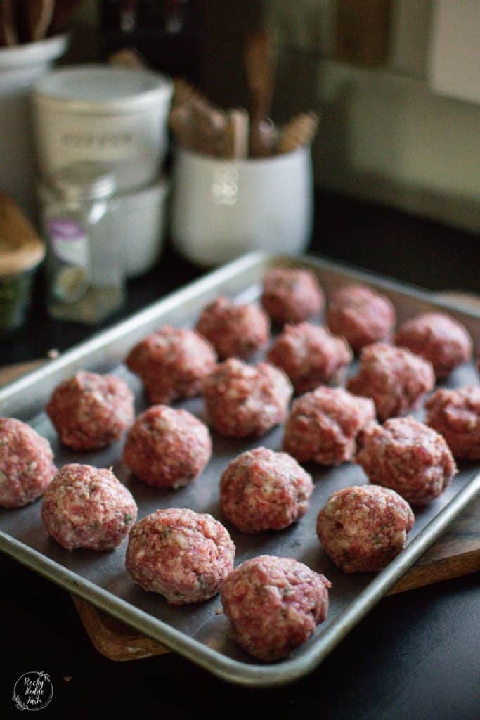Rolled Italian Meatballs ready to be cooked on the stovetop in a cast iron skillet.