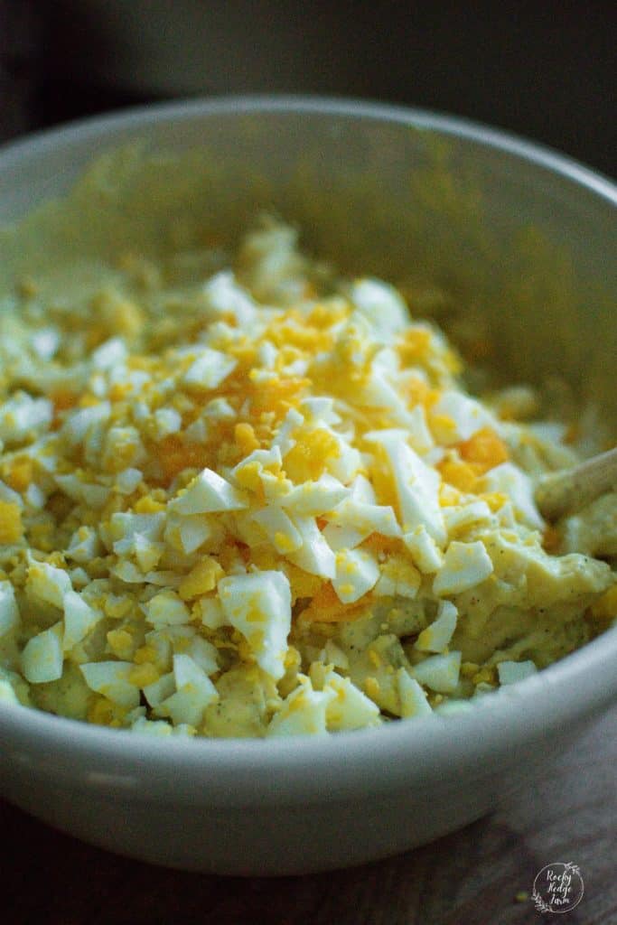 Diced eggs and potatoes in a mixing bowl for potato salad