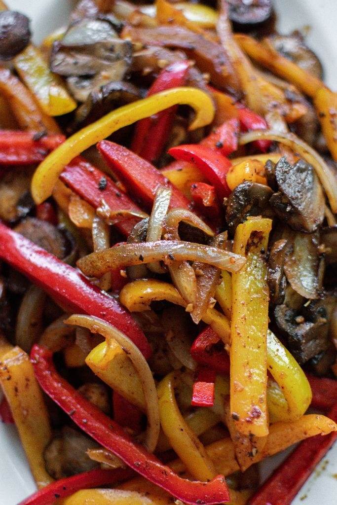 red and yellow bell peppers on top of cooked fajita steak strips