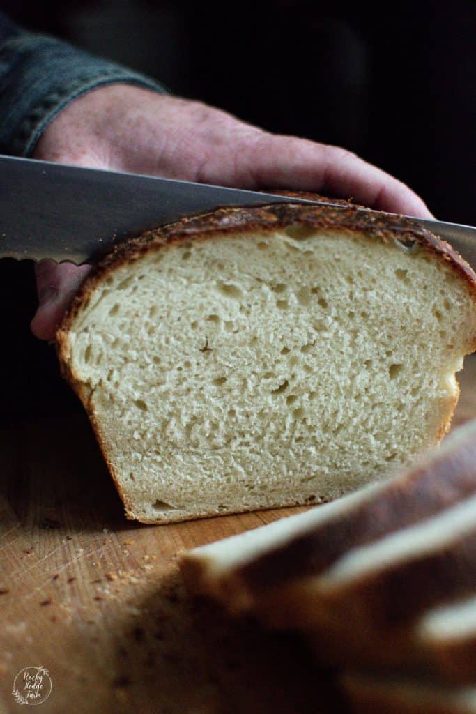 A knife being sliced into a fresh loaf of sourdough bread