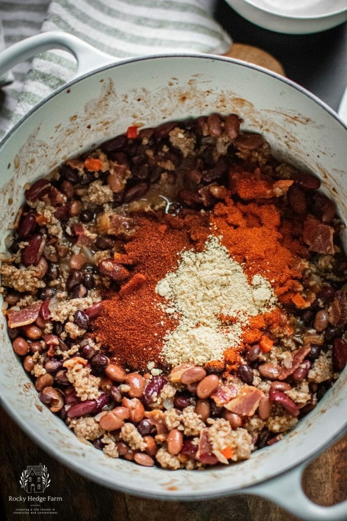 Chili powder, paprika and ground mustard atop beans and bacon for Cowboy Beans