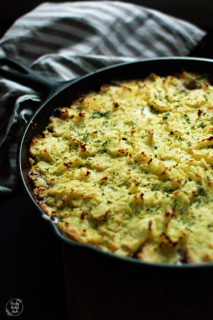 An appetizing shepherd's pie in a cast iron skillet, showcasing layers of ground beef, corn, and creamy mashed potatoes.