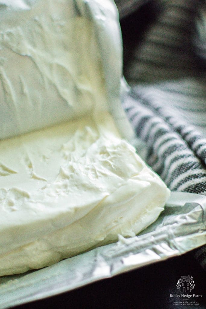 A block of cream cheese sitting on the counter.