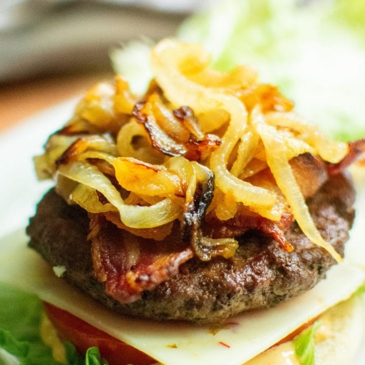 burger on a bun with cheese, caramelized onion and lettuce with tomato
