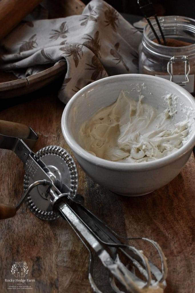 a bowl of cream cheese frosting for cinnamon rolls