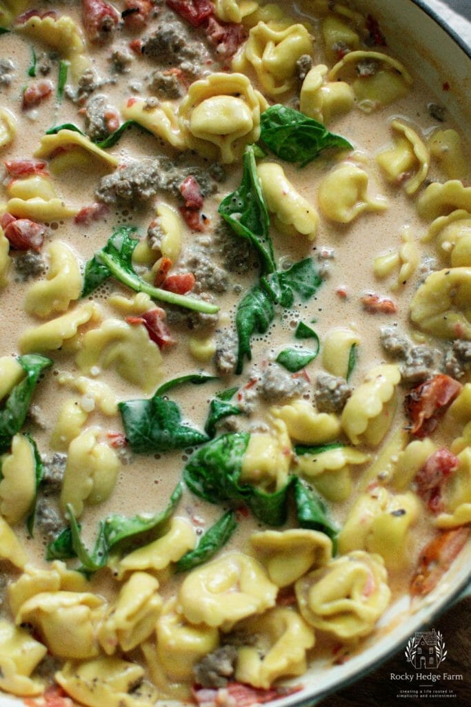 A comforting and creamy tortellini skillet dish with Italian sausage and spinach.