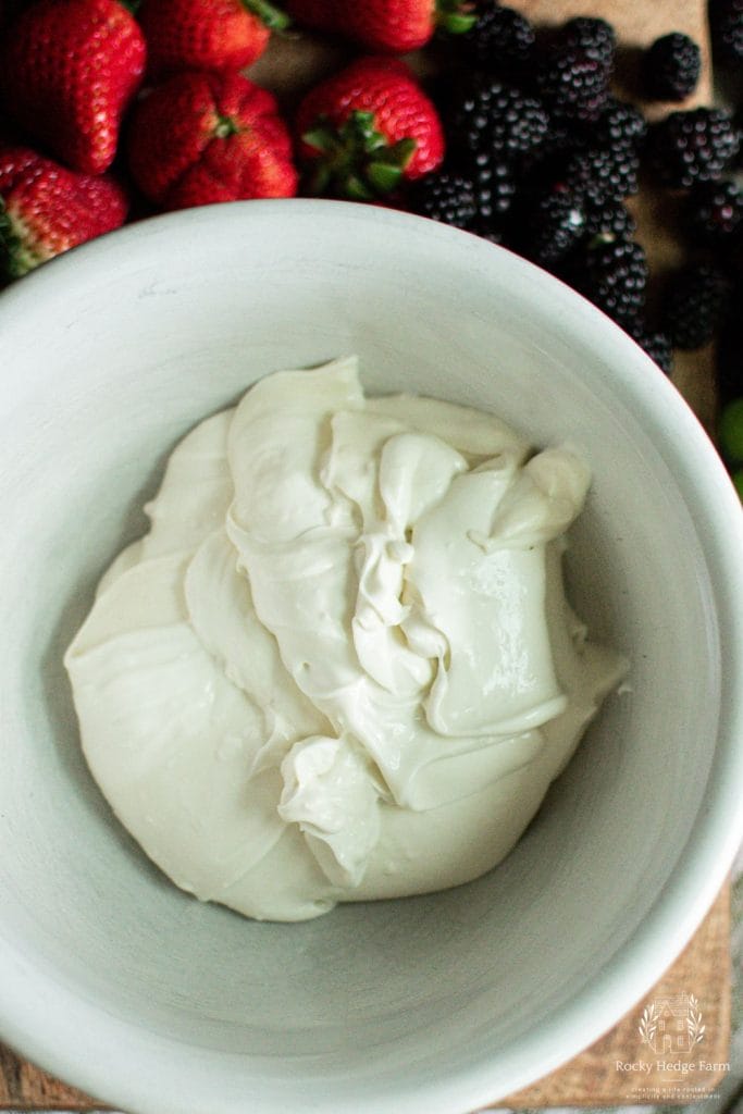 A mixture of cream cheese and yogurt in a white bowl to make cream cheese fruit dip