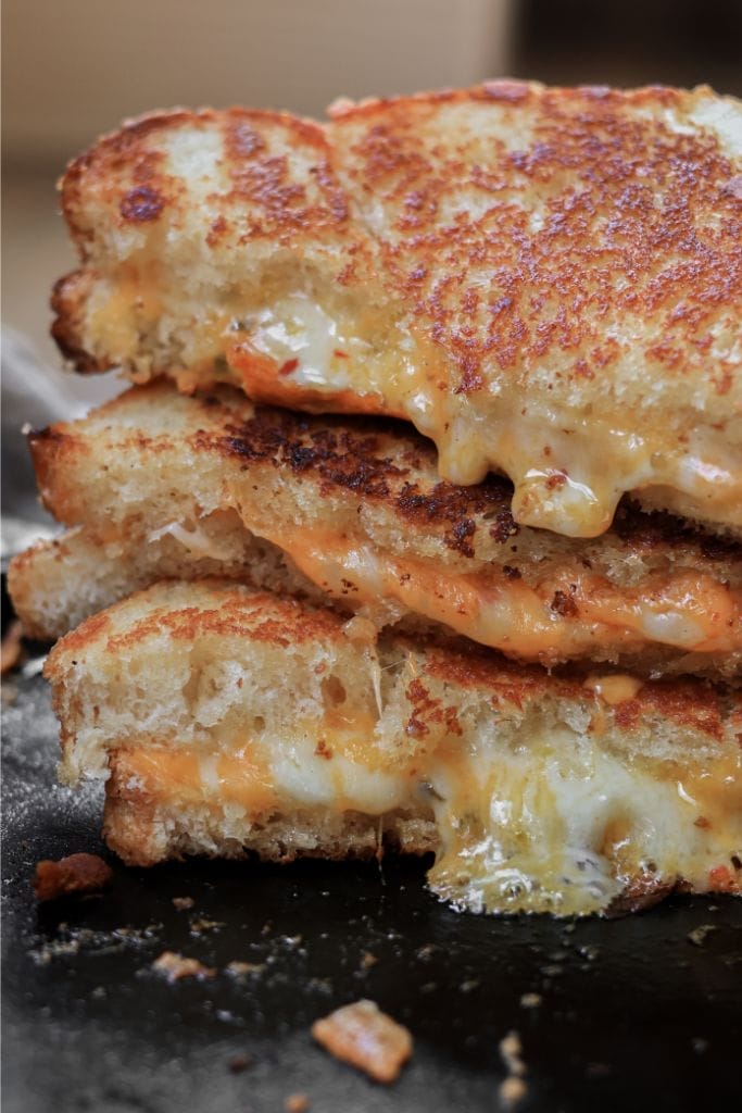 a stack of grilled cheese sandwiches cooked on a cast iron skillet