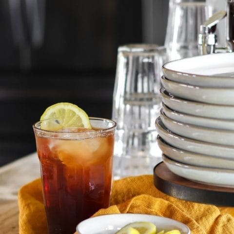 A tall glass pitcher filled with iced tea sits on a table.