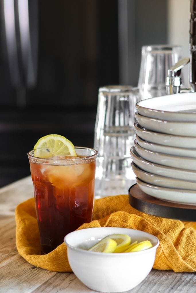 A tall glass pitcher filled with iced tea sits on a table. 