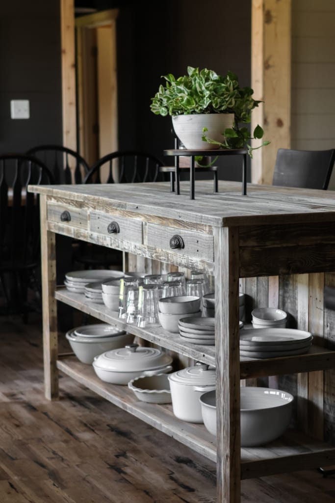 Farmhouse kitchen island with reclaimed wood countertop, offering a breakfast bar with comfortable seating for two and hidden storage in the drawers.
