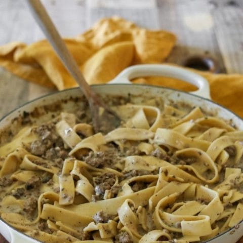 A skillet filled with creamy ground beef stroganoff with egg noodles, mushrooms, and onions.