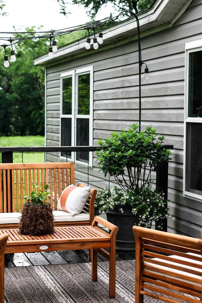 Cozy porch decorated for summer with blooming flowers and ferns.