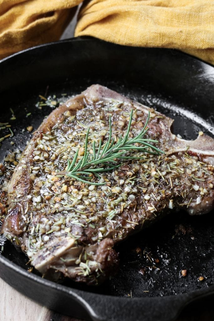 Searing steak in cast iron pan with butter.