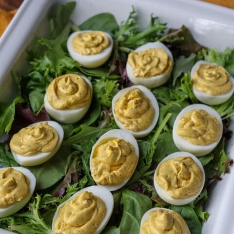 Deviled eggs nestled on a bed of fresh green lettuce with a sprinkle of paprika.