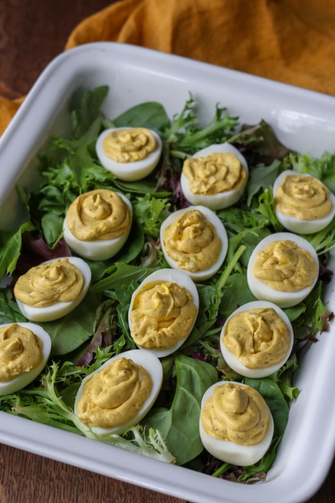 Deviled eggs nestled on a bed of fresh green lettuce with a sprinkle of paprika.