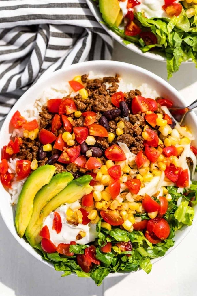 Taco bowl filled with ground beef, rice, avocado, tomatoes