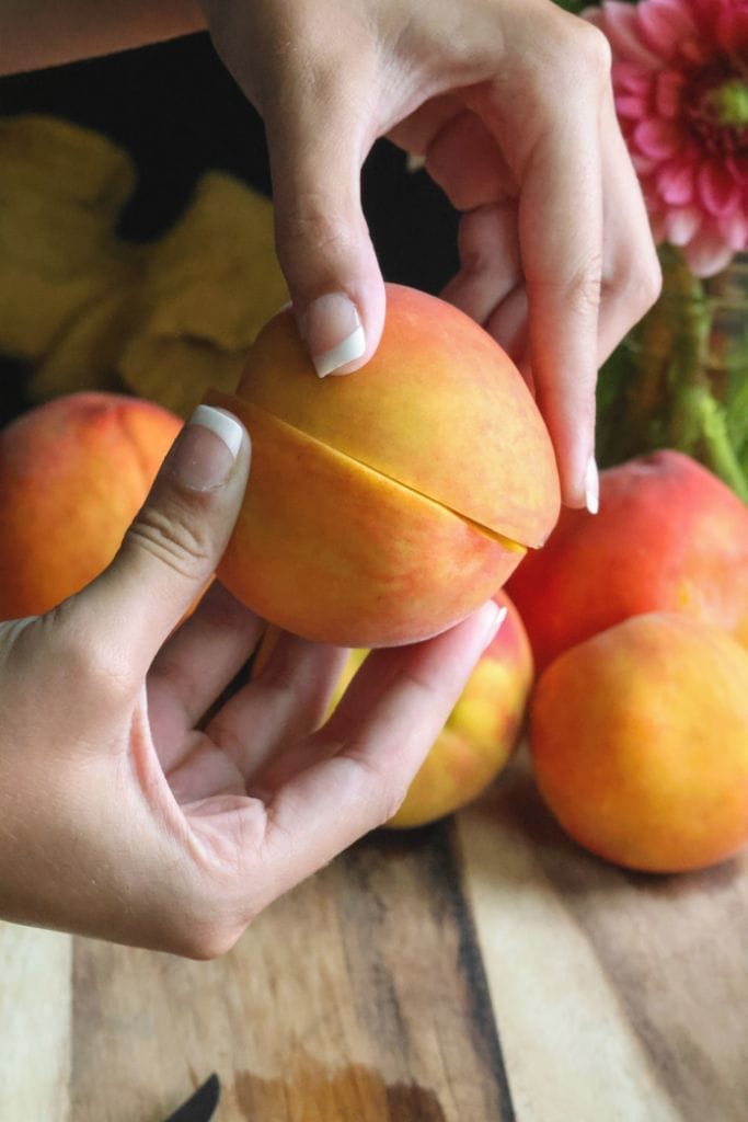 hands twisting a peach in half