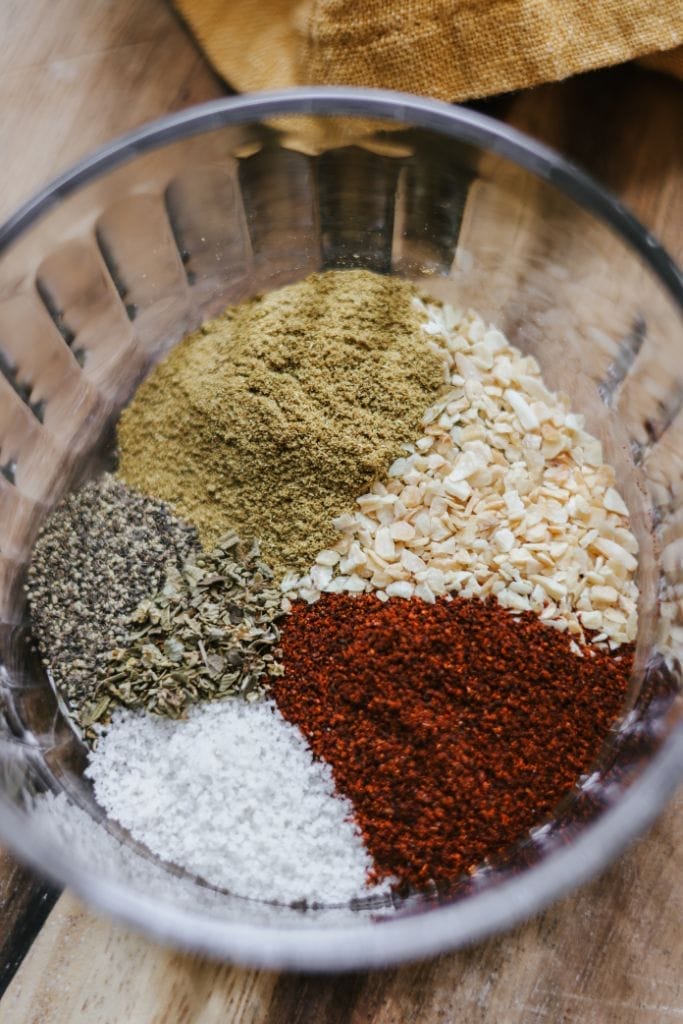 Various spices for taco seasoning, including, oregano, and minced garlic ready to be mixed