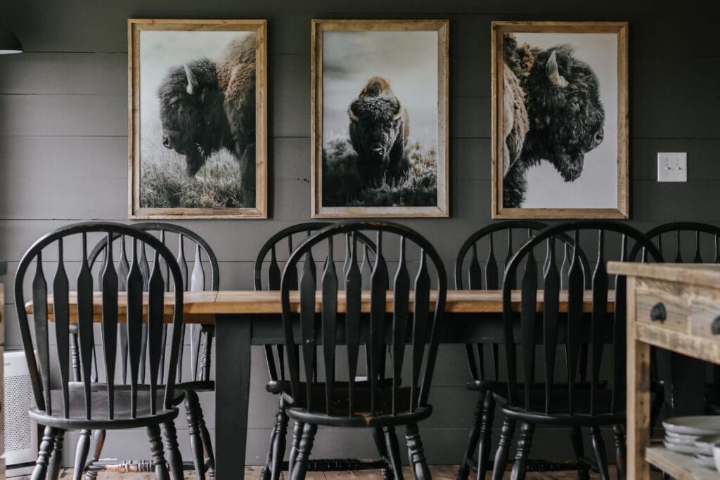 Trio of bison prints by Jeff Brenner Photography displayed on a dark moody wall in a cozy dining room.