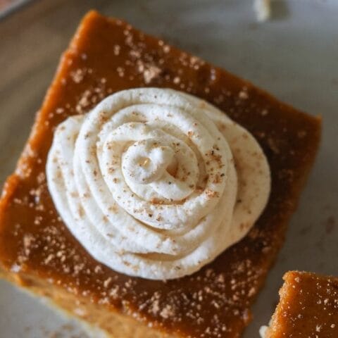 Close-up of pumpkin pie bars topped with fresh whipped cream