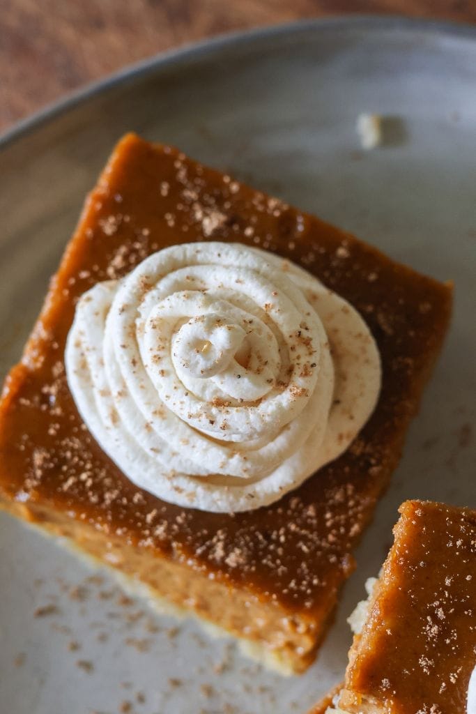 Close-up of pumpkin pie bars topped with fresh whipped cream