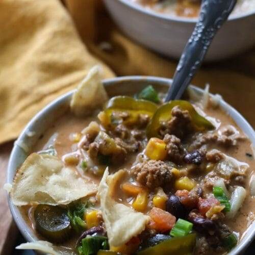 Bowl of creamy taco soup topped with shredded cheese, jalapenos, and tortilla chips