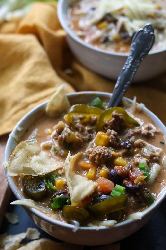 Bowl of creamy taco soup topped with shredded cheese, jalapenos, and tortilla chips