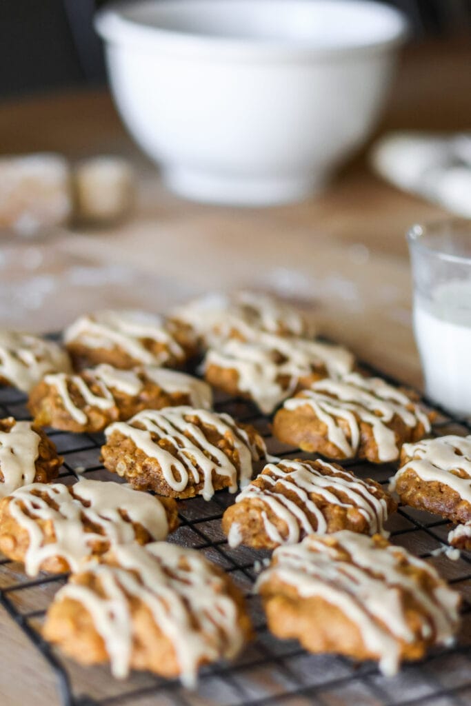 A close-up of a pumpkin oatmeal cookie with a generous drizzle of cinnamon maple glaze