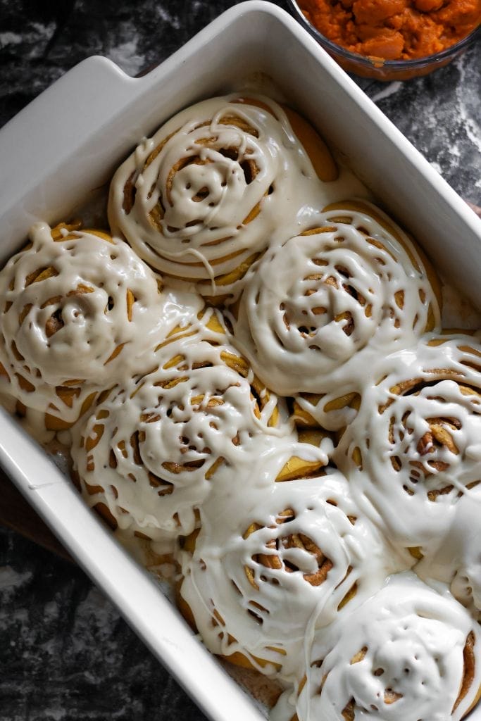 a 9x13 pan filled with cinnamon rolls that are made with pumpkin puree and pumpkin spice