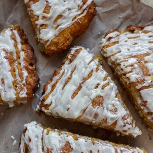 Close-up of a golden, flaky pumpkin scone with a smooth maple glaze.