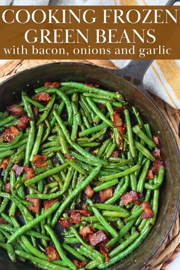 A cast iron skillet filled with green beans tossed in bacon grease, topped with crispy bacon pieces.