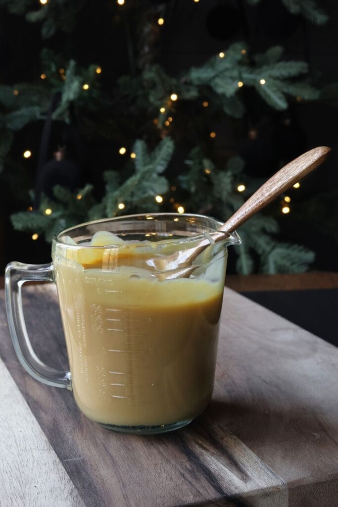 Homemade sweetened condensed milk in a clear jar.