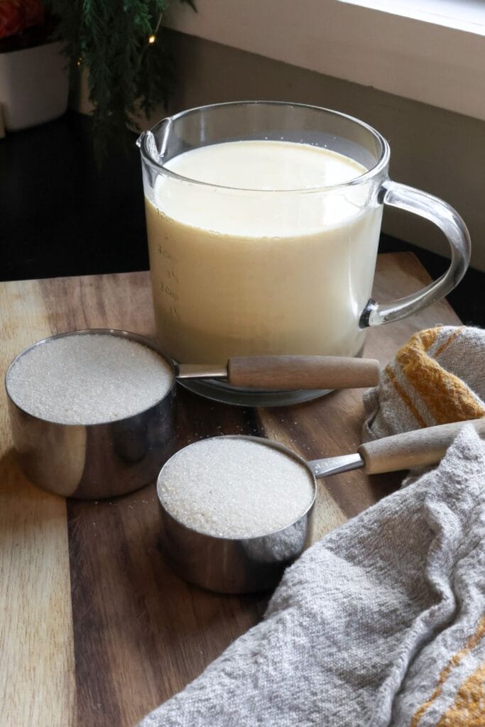 Milk and sugar in measuring cups that are going to be used to make homemade sweetened condensed milk. 