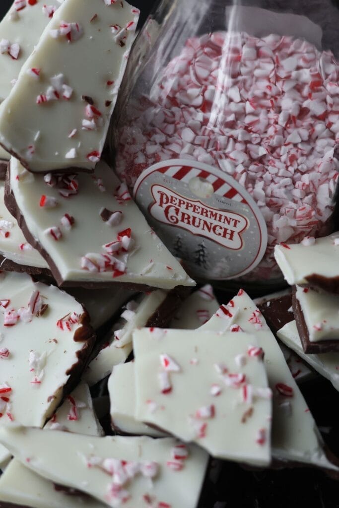 Close-up of homemade peppermint bark candy with white and dark chocolate layers topped with crushed peppermint pieces.