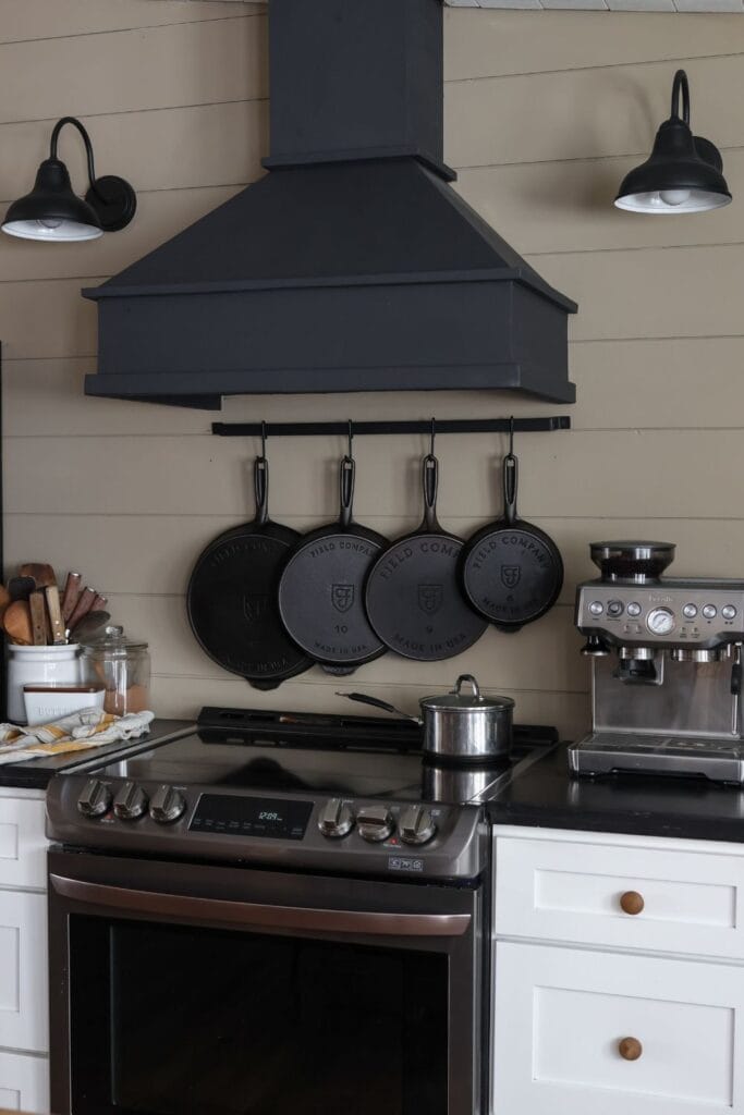 Cast iron skillets hanging in the kitchen, with one skillet heating up on the stovetop.